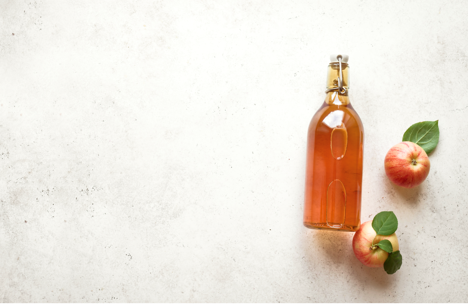 A glass bottle filled with apple juice stands beside two freshly picked applessymbolizing the inherent naturalness and freshness of Eco Flavours juices.